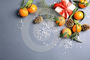 Christmas composition with ripe tangerines, gift box and space for text on grey background