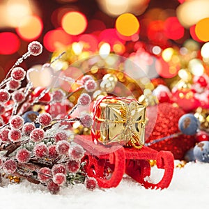 Christmas composition with Santa sleigh, gold gift and colorful Xmas decoration against abstract bokeh light background