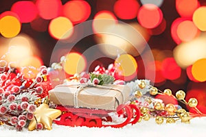 Christmas composition. Santa sleigh, gold gift and colorful Xmas decoration on white snow against abstract bokeh light background