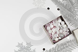 Christmas composition with silver tree branches, snowflakes and box with new year toys on white background