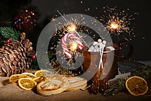 Christmas composition with sparklers and sweets on a dark background.