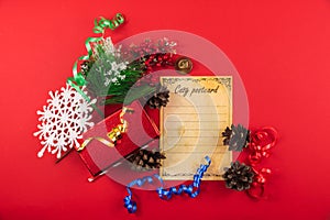 Christmas composition, still life on a red background, top view with ribbons, gifts, postcard, snowflakes and pine cones