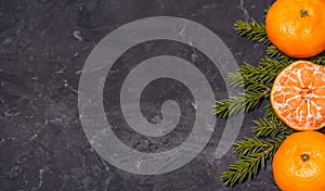 Christmas composition with tangerines on black background, with green spruce tree branch. Flat lay