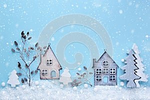 Christmas composition with toy houses, twigs and trees with snow on a blue background. New Year background. Beautiful greeting