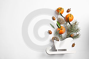 Christmas composition with toy sleigh, ripe tangerines and space for text on white background