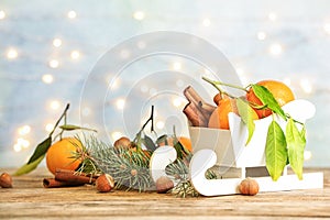 Christmas composition with toy sleigh and ripe tangerines on wooden table.