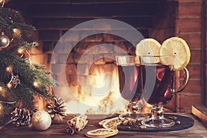 Christmas composition - two glasses with mulled wine on a wooden table near a Christmas tree opposite a burning