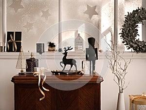 Christmas composition on the vintage shelf in the living room interior with beautiful dark decoration, big window, christmas tree