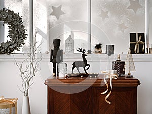 Christmas composition on the vintage shelf in the living room interior with beautiful dark decoration, big window, christmas tree