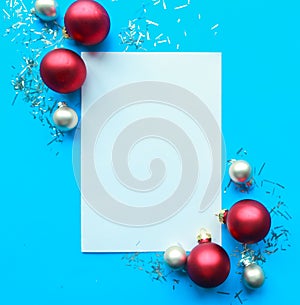 Christmas composition. White mockup blank and red baubles on bright blue background.