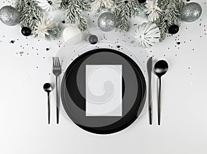 Christmas composition, white and silver decorations, black plate and cutlery, fir tree branches on white background.