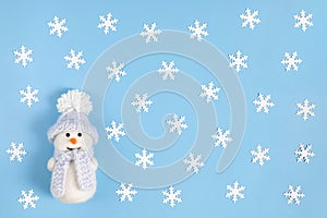 Christmas composition with white snowflakes and a cute snowman on a pastel blue background. Winter concept. Happy new year