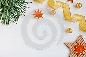 Christmas composition on a white wooden background from pine branches, gold balls, ribbons and stars