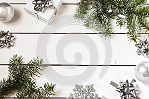 Christmas composition on a white wooden background. white gift boxes, with a silver ribbon with fir branches, toys. Copy space for