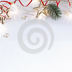 Christmas composition of wooden stars, a garland of white luminous balls, fir branches, bells and a red ribbon on a white