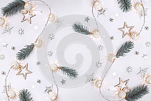 Christmas composition of wooden stars, a garland of white luminous balls, fir branches, bells and snowflakes on a white background