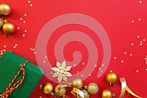 Christmas composition. Wrapped gift, golden toys on red background with golden confetti. new year concept. Greeting card, xmas