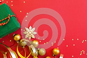 Christmas composition. Wrapped gift, golden toys on red background with golden confetti. new year concept. Greeting card, xmas