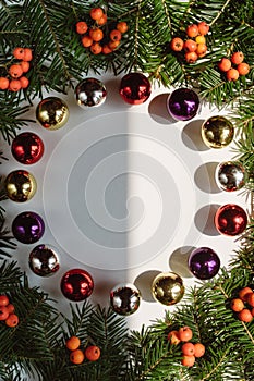 Christmas composition. Wreath made of christmas tree branches and red berries and Christmas toys on white background.