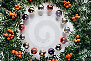 Christmas composition. Wreath made of christmas tree branches and red berries and Christmas toys on white background.