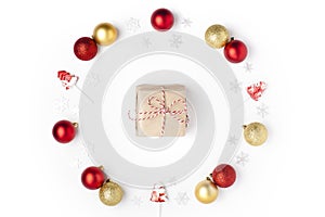 Christmas composition. Wreath made of snowflakes, red, silver, gold balls and lollipops on white background. Gift in the center.