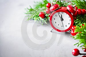 Christmas composition: xmas fir branches, alarm clock and red bells.