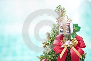 Christmas concept background, Silver gift box with colorful ribbon on Christmas tree over blurred blue water background