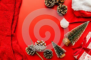 Christmas socks, gifts,pine cones, santa`s hat and fir trees on red background top view flat lay