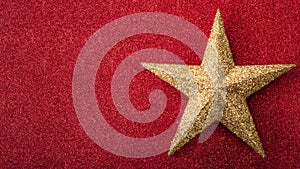 Christmas concept with a glitter golden star on glittery red background full of bling with copy space. The gold and the red