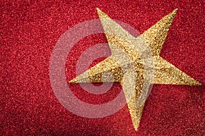 Christmas concept with a glitter golden star on glittery red background full of bling with copy space. The gold and the red