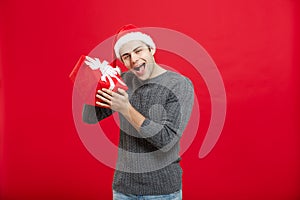 Christmas Concept - handsome young man in sweater with red christmas gift