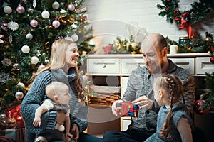 Christmas concept - happy family sitting near the tree and unpacking gifts