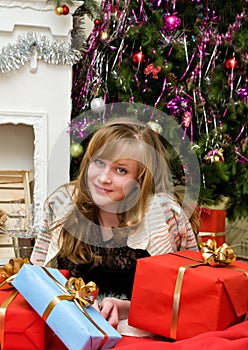 Christmas concept. Happy girl with gifts by the fireplace
