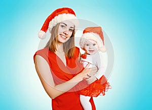 Christmas concept - happy smiling mother and baby in santa red hats