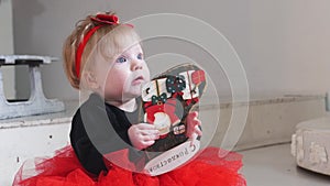 Christmas concept - a little baby girl playing with a toy with `MERRY CHRISTMAS` wrote on it in russian