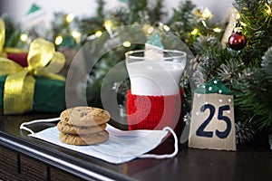 Christmas concept with milk and cookies for Santa. Advent calendar, caronavirus medical mask and Christmas traditions