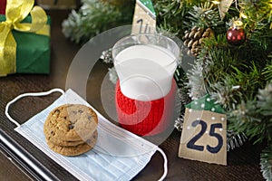 Christmas concept with milk and cookies for Santa. Advent calendar, caronavirus medical mask and Christmas traditions