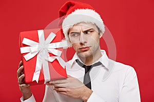 Christmas Concept - portrait close-up Santa christmas businessman over red background holding red gift.