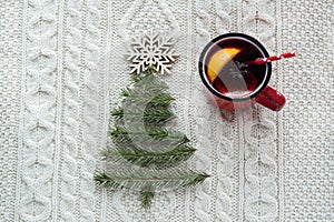 Christmas concept with spruce, fir-tree, cone and mulled wine on white knitted background. Holiday card.