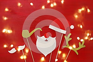 Christmas concept top view image. Santa claus beard and hat on red wooden background.