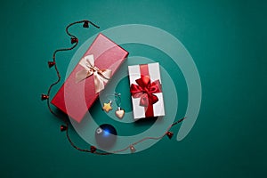Christmas concept. Two red and white gift boxes with bows and decorations on background of green color.