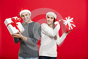 Christmas Concept - Young attractive couple giving gifts to each other celebrating in Christmas day