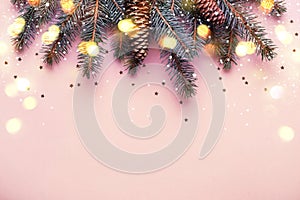 Christmas coniferous border with cones and bokeh lights. Pink background
