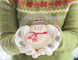 Christmas cookie gingerbread snow man, winter homemade dessert snack in woman baker`s hand in winter glove