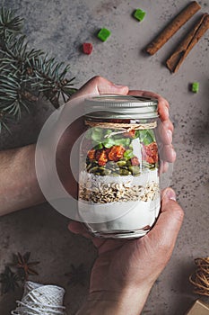 Christmas cookie mix jar. Dry ingredients for cooking Christmas cookies in hands, top view, dark background. Christmas food