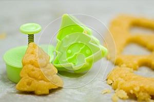 Christmas cookies for children, making gingerbread in shape of fir tree. Raw dough and form for preparation cookie. New year treat