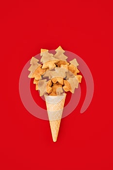 Christmas cookies in Christmas shape in waffle cone on red background. Christmas tree cookies. Festive decorated sweets.