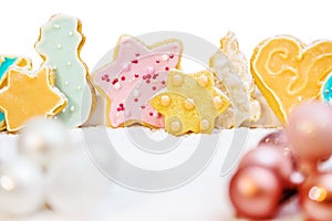 Christmas cookies with colorful frosting, baubles and icing sugar in front of white