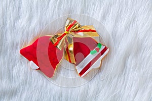 Christmas cookies red bell shape and ribbon on white fur