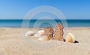 Christmas cookies in the shape of a Christmas tree and a house with small white shells on a sandy beach